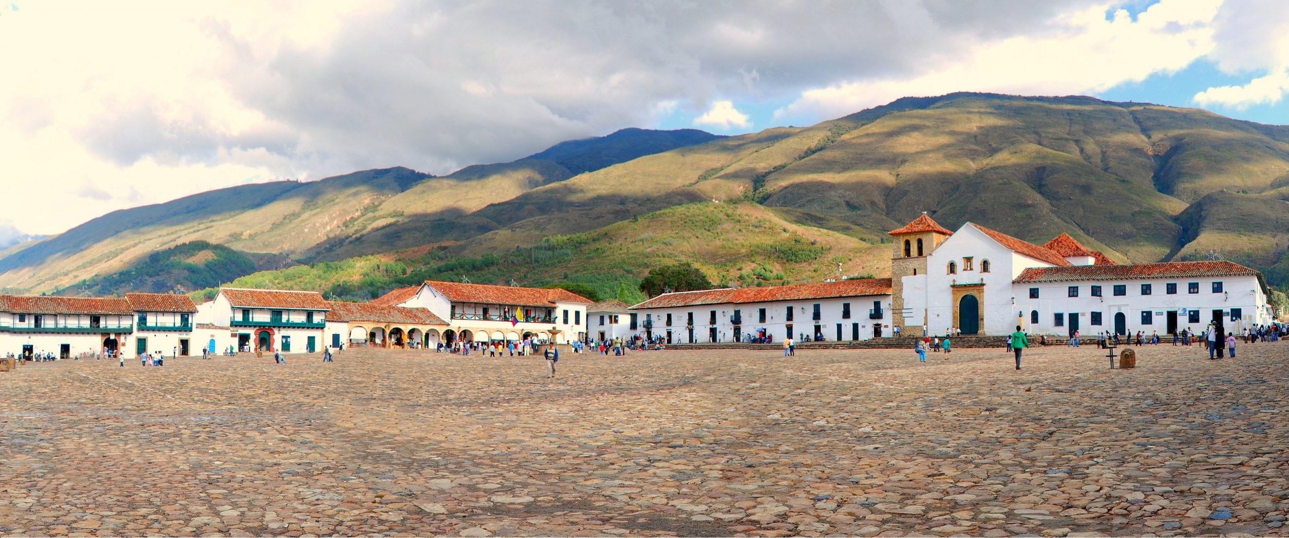 The main square of Villa de Leyva, one of the biggest colonial square in South America, with Nuestra Señora del Rosario church on the right hand side and the beautiful mountains in the background.
